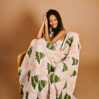 Cozy blanket wrap on chair, pink-and-cream base with green tree pattern