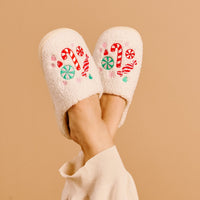 The Darling Effect’s Sugar Rush Fuzzy Slippers feature cozy comfort with embroidered red and white candy canes and green and pink lollipops.