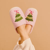 Pink fuzzy slippers with embroidered Christmas tree design, worn with ankle socks