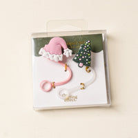 The Darling Effect Santa Baby Straw Topper Set includes leak-resistant silicone straw toppers shaped like a pink Santa hat and a green Christmas tree, packaged in a clear box—perfect Christmas-themed drinkware accessories.