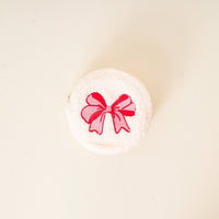 The Darling Effect's Red Bow Circle Teddy Pouch—a round, white, fluffy cosmetics case with an embroidered red bow—makes the perfect travel or festive accessory, shown against a simple light background.