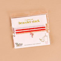 The Darling Effect's Candy Cane Crush Tumbler Bracelet Stack features red, pink, and white beaded bracelets with a candy cane charm, packaged with a tumbler illustration—ideal for tumbler accessory fans.