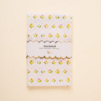 The Handpicked For You Tea Towel by the-darling-effect features a yellow and pink floral pattern on white cotton, wrapped in a scalloped label reading "tea towel" and "Egypt’s cotton kitchen towel." It adds an elegant touch to any home.