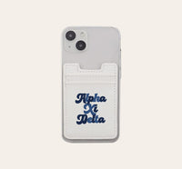 The Darling Effect Alpha Xi Delta Stick-On Phone Wallet in white attaches to a clear smartphone case and features bold dark blue script—an ideal sorority gift.