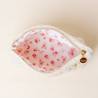 The Darling Effect's Chi Omega Bows & Pearls Teddy Pouch features white sherpa, a pink floral lining, gold zipper, and embroidered bows—making it an adorable gift for any sorority member.