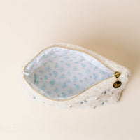 The Darling Effect’s Kappa Kappa Gamma Bows & Pearls Teddy Pouch features a soft white sherpa exterior, gold zipper with a round charm, embroidered bows, and light blue floral lining—an ideal sorority gift.