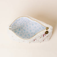 The Darling Effect’s Pi Beta Phi Bows & Pearls Teddy Pouch features white sherpa, pearl and pink embroidered bows, a light blue floral lining, and a gold zipper with charm—perfect as a sorority gift.