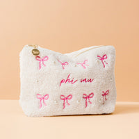 The Darling Effect's Phi Mu Bows & Pearls Teddy Pouch features white fuzzy sherpa, pink embroidered bows, pearl accents, "phi mu" in pink on peach, and a gold heart zipper—an adorable sorority gift.