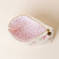 The Darling Effect's Phi Mu Bows & Pearls Teddy Pouch is a fluffy white sherpa pouch with a gold zipper, pink embroidered bows, pearl accents, and a white lining with a pink floral pattern—ideal as a unique sorority gift.