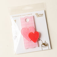 The Charming Gingham Tumbler Lid Tag by The Darling Effect is a pink drink accessory with two hearts, perfect for customizing your Stanley Quencher. It includes cute tumbler cup art on the packaging.