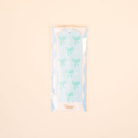The Bows Blue Acrylic Bookmark by the-darling-effect features a light blue design with light green bows and white polka dots. Packaged in plastic, it's a charming gift for book lovers.