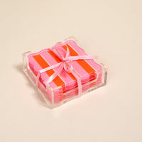 The Darling Effect's Sicily Stripes Pink Table Talk Acrylic Coaster Set comes in a clear acrylic holder, tied with a light pink ribbon—stylish for drinks or chic table décor.