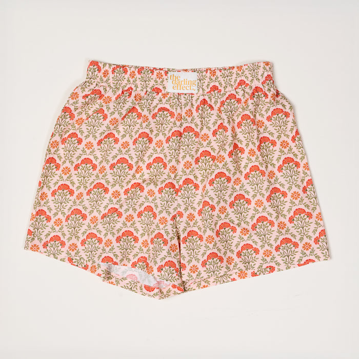 Everbloom Dusty Rose All Day Boxer Shorts by The Darling Effect feature a floral orange and red print with green leaves on light pink, an elastic waistband, and breathable fabric, shown laid flat on a white surface for a comfy look.
