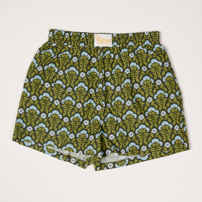 Everbloom Forest Green All Day Boxer Shorts by The Darling Effect feature an elastic waistband, breathable fabric, and a green and blue floral fan pattern on a dark background. An inside label displays the brand name.