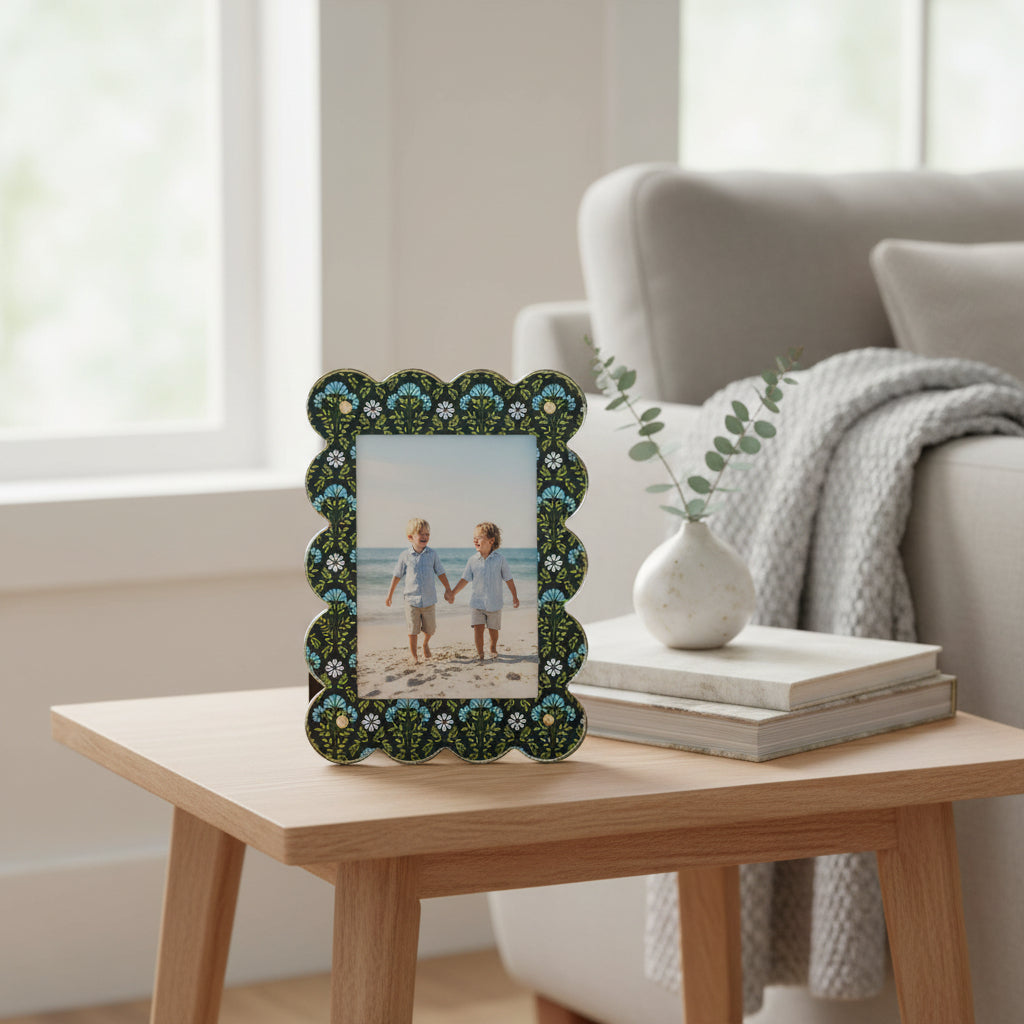 The Everbloom Forest Green Rectangle Scalloped Acrylic Picture Frame by The Darling Effect, featuring two children holding hands on a beach, sits on a wooden side table with greenery and books in a cozy, sunlit living room.
