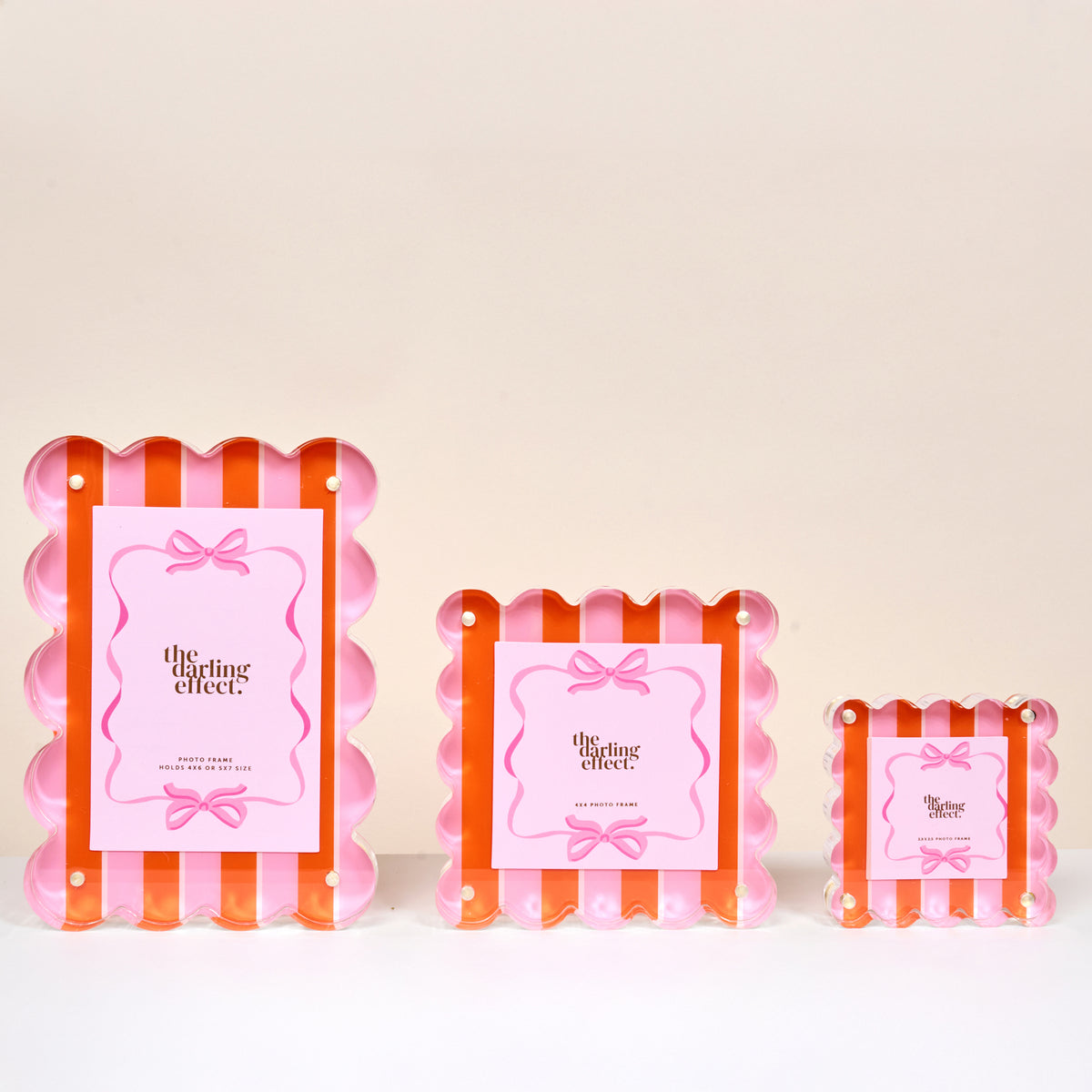 The Darling Effect Sicily Stripes Pink Rectangle Scalloped Acrylic Picture Frame features pink and orange stripes, a pink label with a bow, and comes in small, medium, and large sizes.
