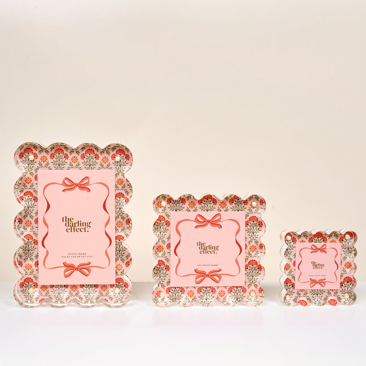Three Everbloom Dusty Rose Little Moments Acrylic Picture Frames by The Darling Effect, featuring scalloped edges and vintage red and green floral accents, are displayed on a white surface for an elegant touch.