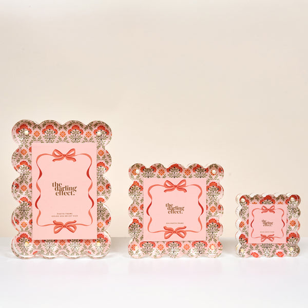 Three Everbloom Dusty Rose Little Moments Acrylic Picture Frames by The Darling Effect, featuring scalloped edges and vintage red and green floral accents, are displayed on a white surface for an elegant touch.