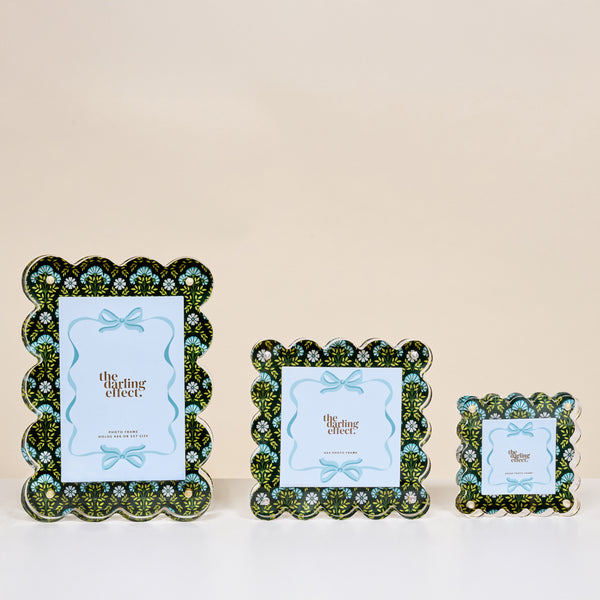 The Darling Effect’s Everbloom Forest Green Little Moments Acrylic Picture Frames, featuring scalloped edges and green, blue, and black floral designs, are shown in small, medium, and large sizes with placeholder cards against a neutral background.