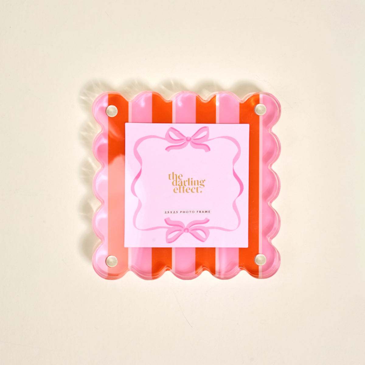 The Sicily Stripes Pink Little Moments Acrylic Picture Frame by The Darling Effect features a square scalloped-edge in pink and orange, four silver screws, a bow card insert, and a secure magnetic closure.
