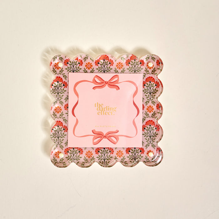 The Everbloom Dusty Rose Square Scalloped Acrylic Picture Frame by The Darling Effect features a decorative tray-like design with floral patterns, pink accents, and modern charm—perfect for displaying treasured memories.