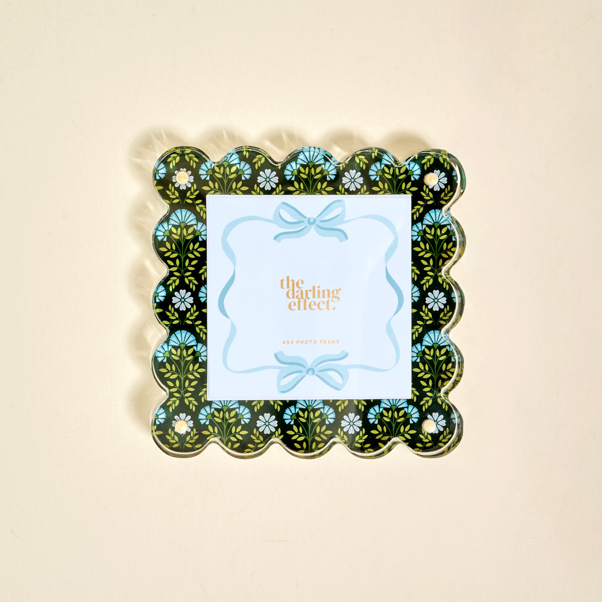 The Everbloom Forest Green Square Scalloped Acrylic Picture Frame by The Darling Effect features a black background with a blue, green, and white floral pattern and holds a card reading "the darling effect" in gold text.