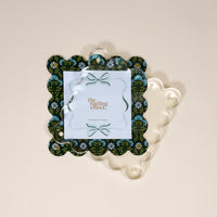 The Darling Effect Everbloom Forest Green Square Scalloped Acrylic Picture Frame features a modern floral design, a clear top layer, and "4X4 PHOTO FRAME" printed at the center.