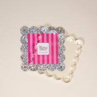 The Darling Effect Silver Glitter Square Scalloped Acrylic Picture Frame features modern design with a wavy clear border and silver glitter, shown displaying a pink and white striped card reading "the darling effect.
