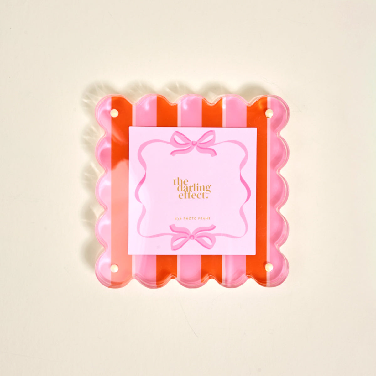 The Sicily Stripes Pink Square Scalloped Acrylic Picture Frame by The Darling Effect features pink and orange stripes, playful scalloped edges, and comes with a decorative brand card, displayed on a light background.