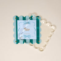 The Darling Effect Sicily Stripes Teal Square Scalloped Acrylic Picture Frame features green and light blue stripes, a clear acrylic overlay, and ribbon and bow details—a modern way to showcase your favorite memories.