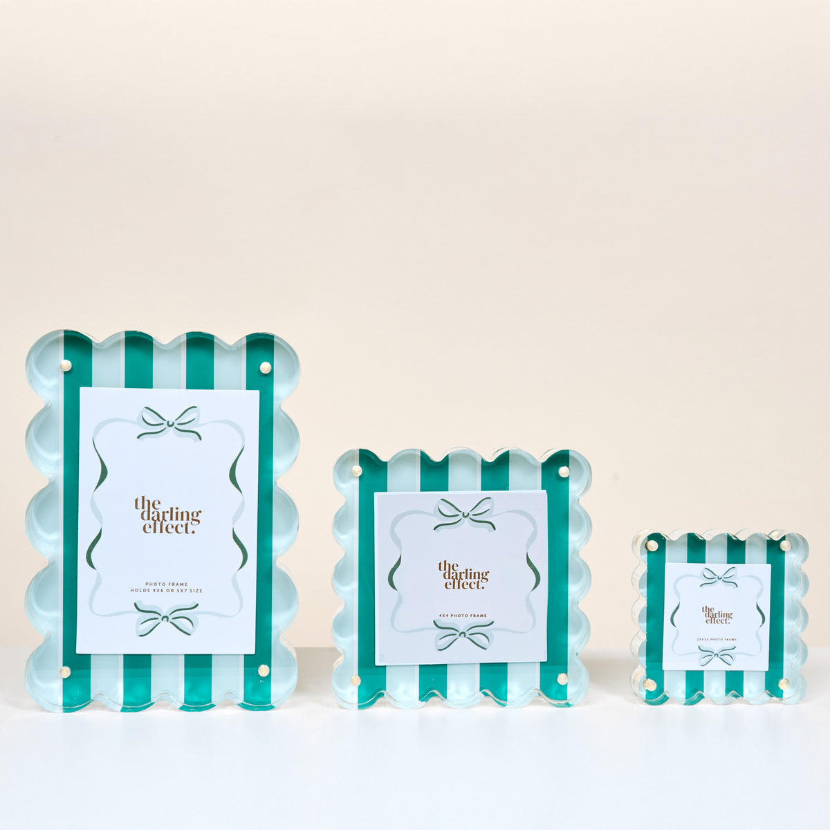 Three Sicily Stripes Teal Square Scalloped Acrylic Picture Frames by The Darling Effect, featuring teal and white stripes, bow accents, and a modern design, are arranged from largest to smallest on a white surface.