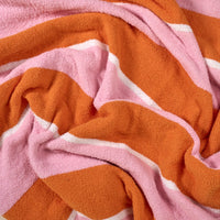 A close-up of The Darling Effect Sicily Stripes Pink Cozy Dreams Luxe Blanket, showcasing its soft microfiber texture with bold wavy orange and pink stripes, thin white accents, and a plush, crumpled surface.