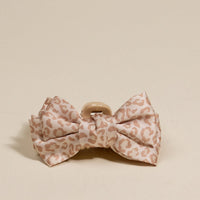 The Darling Effect’s Cheetah Mini Satin Bow Claw Clip features a soft pink and beige leopard print and makes the perfect accessory, shown against a neutral background.