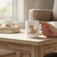 The Darling Effect's Kitty Corner 11 oz Cozy Cute Ceramic Mug features a cartoon brown cat and yarn with a golden handle, steaming on a wooden table—ideal for savoring your favorite coffee or tea.