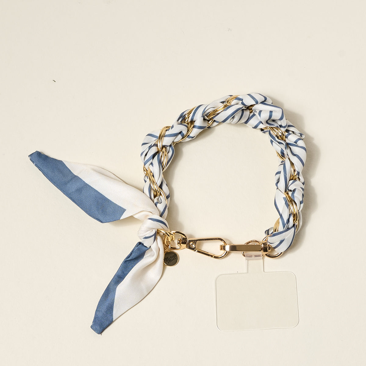 The Darling Effect's Bluebell Stripe Call Me Later Phone Scarf is a chic accessory, featuring a braided blue and white scarf interwoven with a gold-tone chain, a gold clasp, and a clear phone tab.