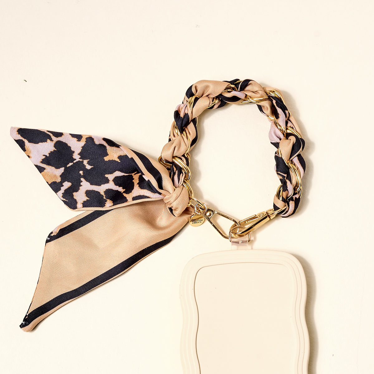 The Darling Effect's Cheetah Call Me Later Phone Scarf, featuring a beige and gold-tone chain lanyard with leopard print, is paired with a light beige badge holder—a chic accessory for everyday style.