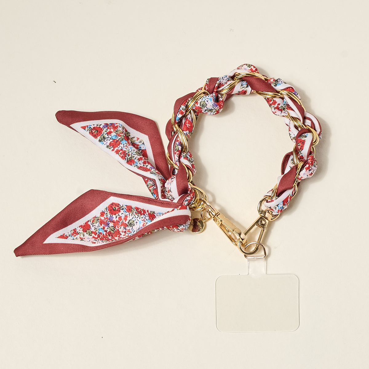 The Darling Effect’s Crimson Rose Call Me Later Phone Scarf features a gold-tone chain lanyard with an interwoven red floral scarf, clear plastic ID badge holder, and gold clip, shown on a light beige background.