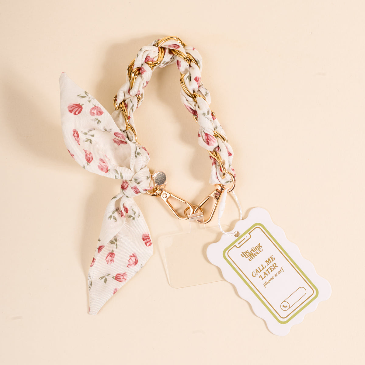 The Darling Effect’s Garden Party Call Me Later Phone Scarf is a floral keychain with a braided strap, gold clasp, and bow. On a light background, it displays a scalloped tag reading CALL ME with a phone graphic.