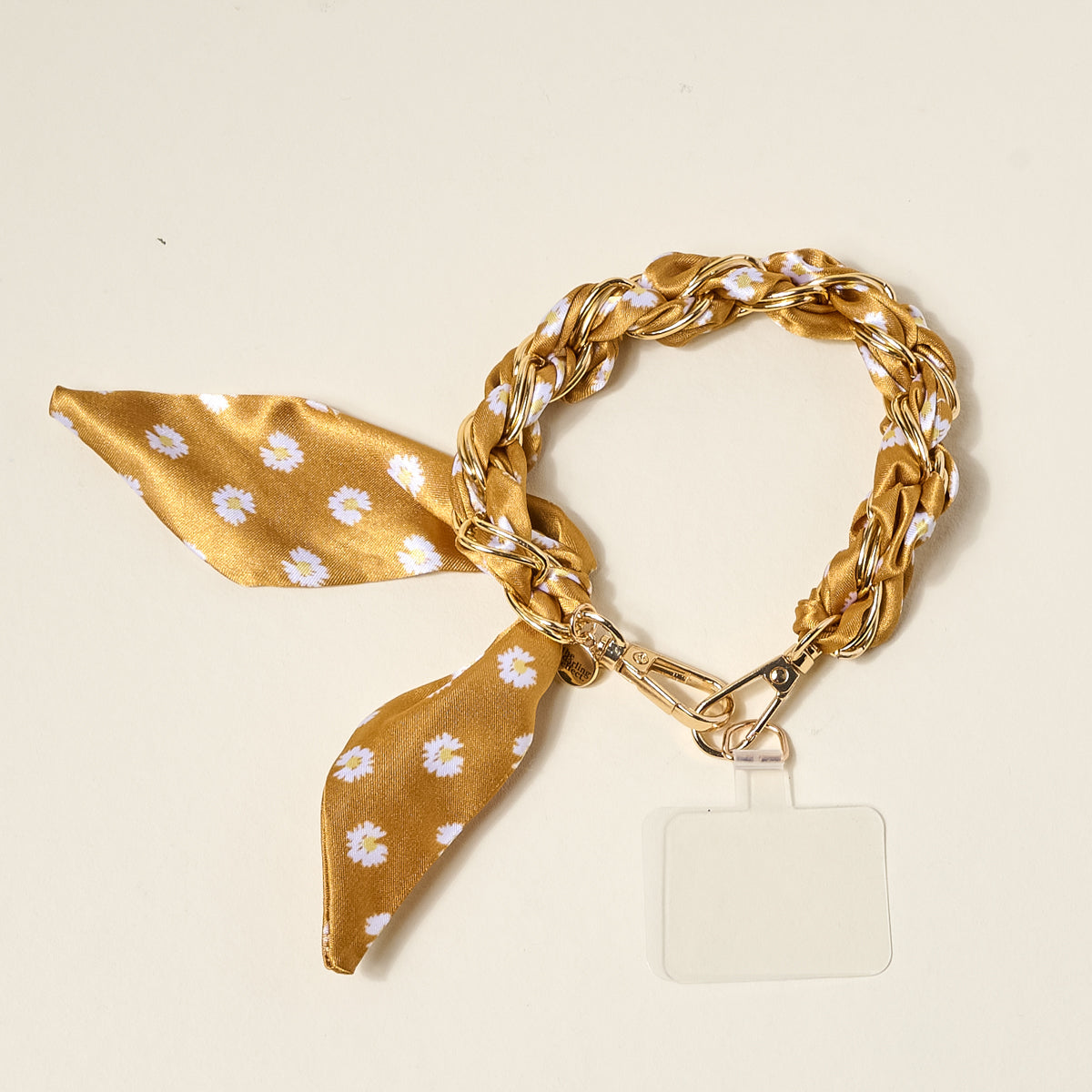 The Darling Effect’s Honey Blossom Call Me Later Phone Scarf pairs a daisy-print satin ribbon and gold braid with a clear badge holder for a stylish, practical accessory.