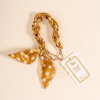 The Darling Effect's Honey Blossom Call Me Later Phone Scarf features a gold and white floral fabric keychain with braided loop, a matching knotted phone scarf, metal clip, and a white CALL ME tag for your number.