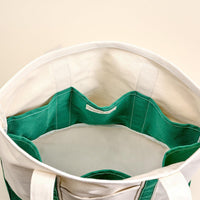 Top view of The Darling Effect's Dark Green The Signature Canvas Tote Bag, featuring durable handles, a green and white lining, and multiple interior pockets—ideal for everyday use.
