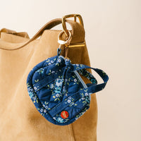 The Endless Daydream Navy Itty Bitty Duffle Bag Charm by the-darling-effect hangs from a tan suede hobo bag strap, adding a stylish accent.