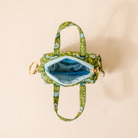 The Darling Effect’s Everbloom Forest Green Itty Bitty Duffle Bag Charm is shown open on a light beige background, featuring a blue striped interior—perfect as a stylish accessory or paired with other bag charms for extra flair.