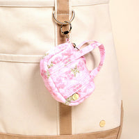 The Oh So Fancy Pink Itty Bitty Duffle Bag Charm by The Darling Effect hangs from a cream canvas tote, adding a chic touch as the perfect accessory.