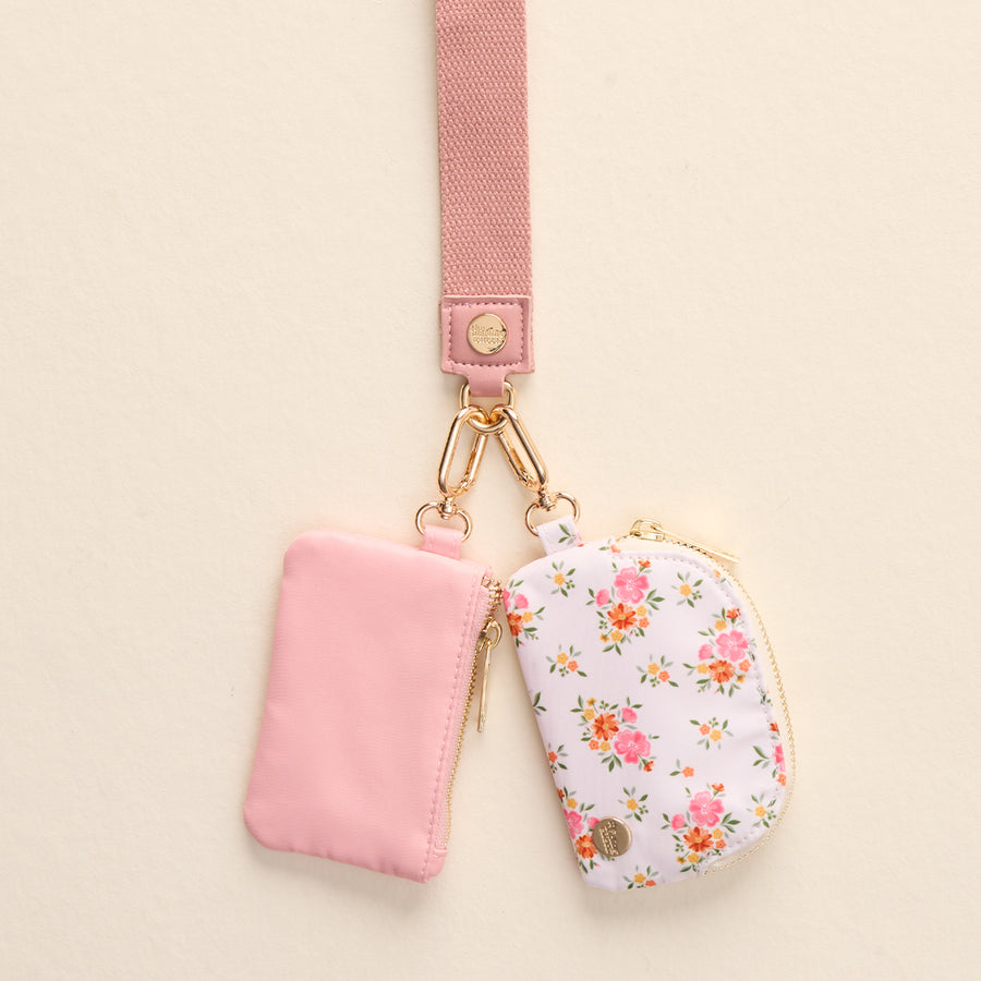 The-darling-effect's Endless Daydream Cream Dynamic Duo Pouch Wristlet features two chic pouches on a pink lanyard, offering a hands-free, stylish accessory against a beige background.