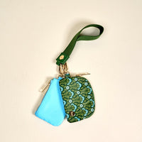 The Darling Effect Everbloom Forest Green Dynamic Duo Pouch Wristlet features a small zippered pouch set and green patterned case on a luxe gold keyring with a fabric wrist strap, offering hands-free convenience. Displayed on a light background.