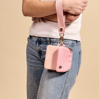 A person in a white shirt and jeans holds The Darling Effect Blush Dynamic Duo Pouch Luxe Wristlet, featuring two matching pink pouches.