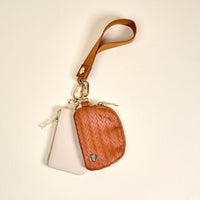 The Darling Effect's Brown Dynamic Duo Pouch Luxe Wristlet features a tan woven section and plain beige area, paired with a brown leather strap and gold clasp for hands-free convenience, shown on a neutral background.