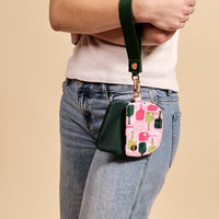 The-darling-effect Pickleball Party Dynamic Duo Pouch Wristlet in pink with pickleball paddle print, gold hardware, and zip closure clips to a dark green crossbody strap. Shown on a model in jeans and a white tee.