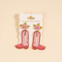 The Darling Effect Cowgirl Boot Beaded Earrings feature pink hand-beading, pearls, rhinestones, and floral details—perfect for adding a playful touch to your jewelry collection.